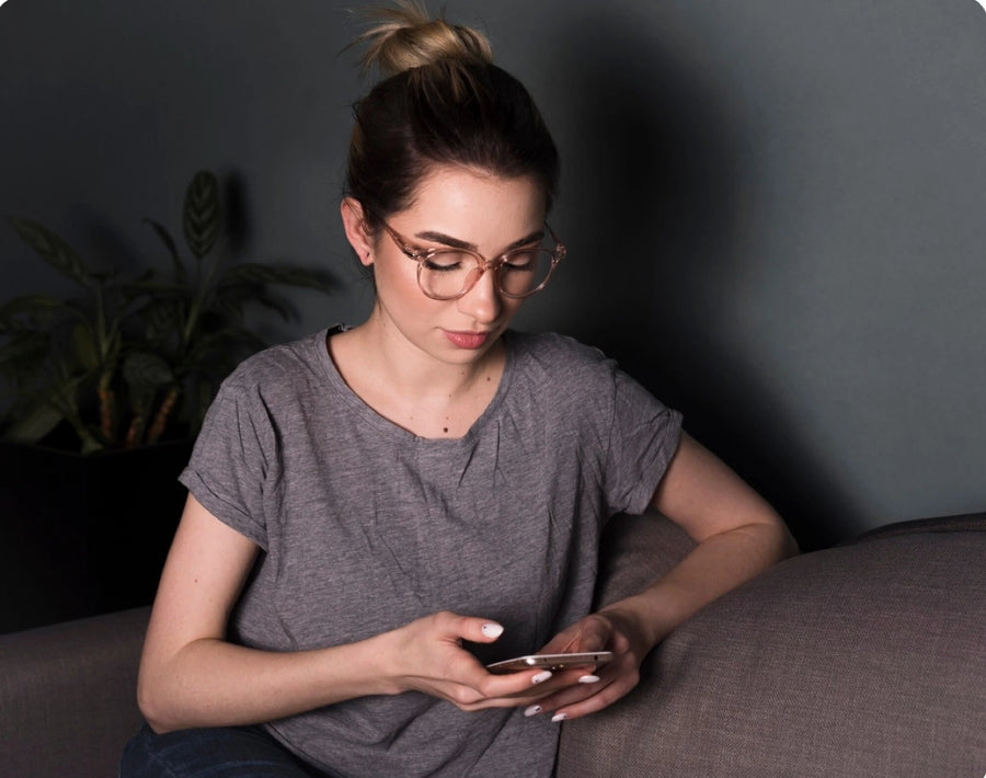 Femme qui scrolle son téléphone sur le canapé le soir